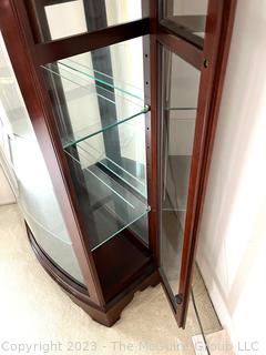 Contemporary Lighted Wood and Glass Bow Front Curio Display Cabinet with Adjustable Glass Shelves, Sliding Side Door and Mirrored Back. This is the second of two  offered in this auction.  26w" x 15"d x 78"t