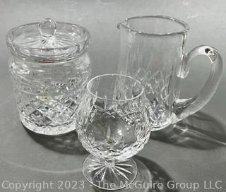 Three (3) Pieces of Waterford Crystal in the Lismore Pattern Including a Biscuit Barrel,  Pitcher and Goblet. Measures approximately 8" tall.