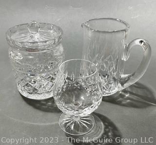 Three (3) Pieces of Waterford Crystal in the Lismore Pattern Including a Biscuit Barrel,  Pitcher and Goblet. Measures approximately 8" tall.