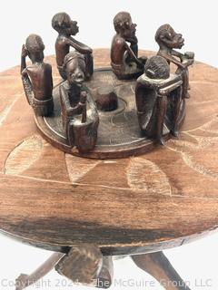 Carved Wood Tripod Table From Zimbabwe with African Wooden Disc With Six Men Seated.