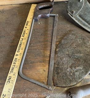 Grouping of Bench Tools Including Sickles, Hack Saw, Horse Bits, Hand Drill Brace and Large Axe Head  