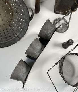 Assorted antique kitchen tools: colander, muffin tray, masher, tin, etc