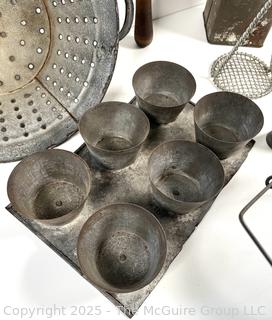 Assorted antique kitchen tools: colander, muffin tray, masher, tin, etc