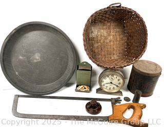????????  Eclectic grouping: metal tray; coffee tin; Hanging match holder; hack saw; alarm clock and wicker basket 