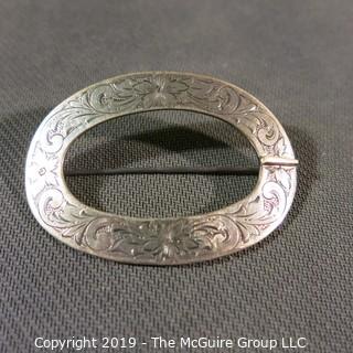 Jewelry: 2.75 x 2 in. sterling oval buckle style brooch and engraved with 4 flowers and acanthus leaves.  Slight damage on right side.