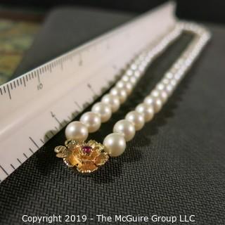 Jewelry: Lovely, knotted 15 in. strand of 7mm, white, Akoya pearls with 14K Yellow gold floral clasp with safety, and center 2.5 mm ruby. (TMG 757)