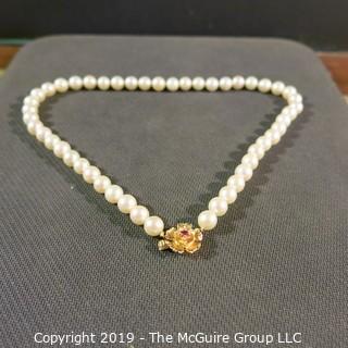 Jewelry: Lovely, knotted 15 in. strand of 7mm, white, Akoya pearls with 14K Yellow gold floral clasp with safety, and center 2.5 mm ruby. (TMG 757)