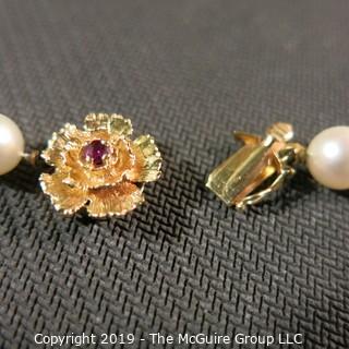 Jewelry: Lovely, knotted 15 in. strand of 7mm, white, Akoya pearls with 14K Yellow gold floral clasp with safety, and center 2.5 mm ruby. (TMG 757)