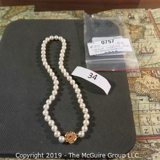 Jewelry: Lovely, knotted 15 in. strand of 7mm, white, Akoya pearls with 14K Yellow gold floral clasp with safety, and center 2.5 mm ruby. (TMG 757)