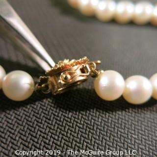 Jewelry: Lovely, knotted 15 in. strand of 7mm, white, Akoya pearls with 14K Yellow gold floral clasp with safety, and center 2.5 mm ruby. (TMG 757)