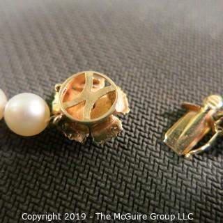 Jewelry: Lovely, knotted 15 in. strand of 7mm, white, Akoya pearls with 14K Yellow gold floral clasp with safety, and center 2.5 mm ruby. (TMG 757)