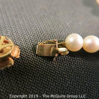 Jewelry: Lovely, knotted 15 in. strand of 7mm, white, Akoya pearls with 14K Yellow gold floral clasp with safety, and center 2.5 mm ruby. (TMG 757)