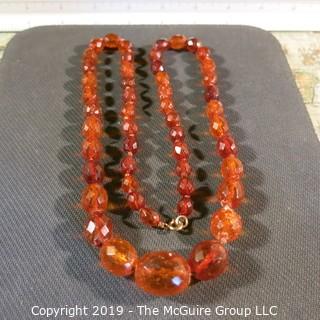 Jewelry: Necklace of 51 graduated and faceted Amber beads, 9 x 7 – 22 x 18mm, knotted – moderate wear.