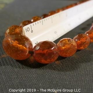 Jewelry: Necklace of 51 graduated and faceted Amber beads, 9 x 7 – 22 x 18mm, knotted – moderate wear.