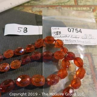 Jewelry: Necklace of 51 graduated and faceted Amber beads, 9 x 7 – 22 x 18mm, knotted – moderate wear.