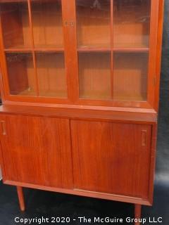 Danish Mid Century Stepped Back glass front cabinet; two doors over two sliding doors; base is 36W x 28T x 17D; top is 36W x 36T x 13D