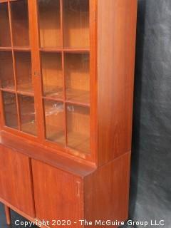 Danish Mid Century Stepped Back glass front cabinet; two doors over two sliding doors; base is 36W x 28T x 17D; top is 36W x 36T x 13D