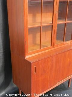 Danish Mid Century Stepped Back glass front cabinet; two doors over two sliding doors; base is 36W x 28T x 17D; top is 36W x 36T x 13D