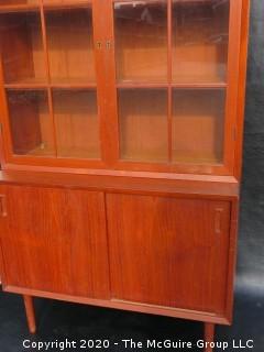 Danish Mid Century Stepped Back glass front cabinet; two doors over two sliding doors; base is 36W x 28T x 17D; top is 36W x 36T x 13D