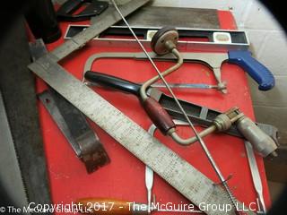 Collection of tools including bar clamps, metal rulers, square, hand saws, hand drill, hack saw, scroll saw