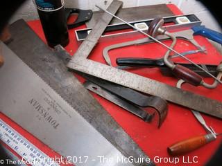 Collection of tools including bar clamps, metal rulers, square, hand saws, hand drill, hack saw, scroll saw