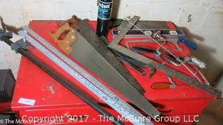 Collection of tools including bar clamps, metal rulers, square, hand saws, hand drill, hack saw, scroll saw