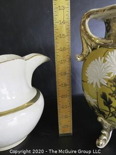 Large Ceramice Pitcher with Gilt Decoration and Yellow Urn Style Vase with White Floral Decoration.  Measures approximately 14". 