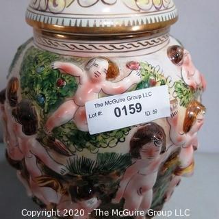 Vintage Porcelain Hand Painted Italian Capodimonte Urn with Lid and Handles with Frolicking Figurals & Cherubs. Several Repairs and chips. Measures approximately 17" tall with lid. 
