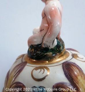 Vintage Porcelain Hand Painted Italian Capodimonte Urn with Lid and Handles with Frolicking Figurals & Cherubs. Several Repairs and chips. Measures approximately 17" tall with lid. 
