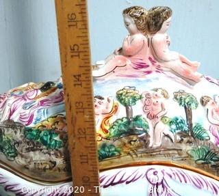 Vintage Porcelain Hand Painted Italian Capodimonte Centerpiece Covered Dish with Lid and Handles with Frolicking Figurals & Cherubs.  Measures approximately 22" long and 16"tall with lid. 
