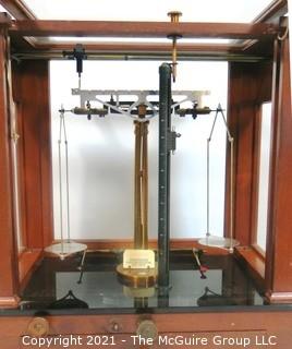 Antique Triple Beam Balance Gold or Apothecary Cabinet Scale in a Glass and Wood Case by Christian Becker, New York.. It has glass panels on all four side and has one drawer with weights and other accessories.   It measures approximately 18" x 16" x 9".