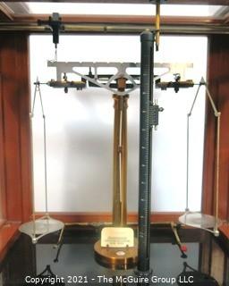 Antique Triple Beam Balance Gold or Apothecary Cabinet Scale in a Glass and Wood Case by Christian Becker, New York.. It has glass panels on all four side and has one drawer with weights and other accessories.   It measures approximately 18" x 16" x 9".