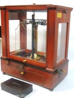 Antique Triple Beam Balance Gold or Apothecary Cabinet Scale in a Glass and Wood Case by Christian Becker, New York.. It has glass panels on all four side and has one drawer with weights and other accessories.   It measures approximately 18" x 16" x 9".