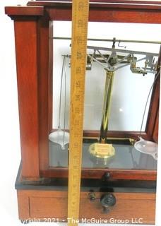 Antique Triple Beam Balance Gold or Apothecary Cabinet Scale in a Glass and Wood Case Made by Voland & Sons of New Rochelle, NY, 1912. It has glass panels on all four side and has one drawer with box of scale weights. It measures approximately 21" x 16" x 9".