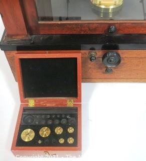 Antique Triple Beam Balance Gold or Apothecary Cabinet Scale in a Glass and Wood Case Made by Voland & Sons of New Rochelle, NY, 1912. It has glass panels on all four side and has one drawer with box of scale weights. It measures approximately 21" x 16" x 9".