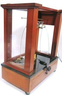 Antique Triple Beam Balance Gold or Apothecary Cabinet Scale in a Glass and Wood Case Made by Voland & Sons of New Rochelle, NY, 1912. It has glass panels on all four side and has one drawer with box of scale weights. It measures approximately 21" x 16" x 9".