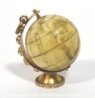 Antique Scrimshaw Articulated Globe Charm or Pendant in 14kt Gold Stand with Raw Sapphire Decorative Gemstones. It measures approximately 1 1/4" tall and weights 10.7g.