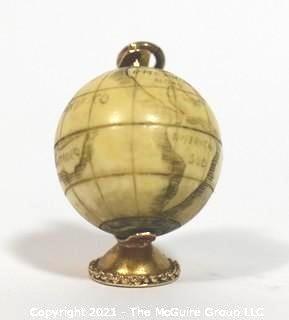 Antique Scrimshaw Articulated Globe Charm or Pendant in 14kt Gold Stand with Raw Sapphire Decorative Gemstones. It measures approximately 1 1/4" tall and weights 10.7g.