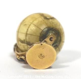 Antique Scrimshaw Articulated Globe Charm or Pendant in 14kt Gold Stand with Raw Sapphire Decorative Gemstones. It measures approximately 1 1/4" tall and weights 10.7g.