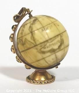 Antique Scrimshaw Articulated Globe Charm or Pendant in 14kt Gold Stand with Raw Sapphire Decorative Gemstones. It measures approximately 1 1/4" tall and weights 10.7g.