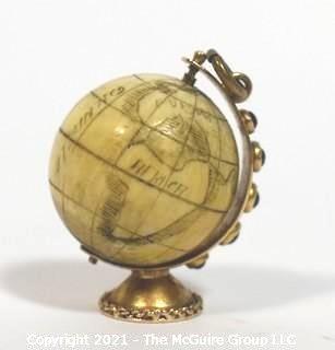 Antique Scrimshaw Articulated Globe Charm or Pendant in 14kt Gold Stand with Raw Sapphire Decorative Gemstones. It measures approximately 1 1/4" tall and weights 10.7g.