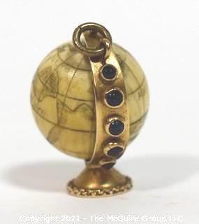 Antique Scrimshaw Articulated Globe Charm or Pendant in 14kt Gold Stand with Raw Sapphire Decorative Gemstones. It measures approximately 1 1/4" tall and weights 10.7g.