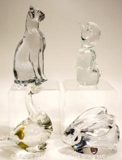 Group of Four (4) Crystal Art Glass Figurines.  Includes Royal Krona Sweden Crystal Art Glass Lead Crystal Penguin Signed By Mats Jonasson, Orrefors Clear Crystal Rabbit Figurine Signed By Artist, Sweden by Granna Glas. Swan & Silvestri Art Glass Clear Sitting Cat . 