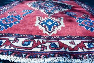 Hand Woven Persian Rug on Red Background. Measures approximately 60" x 89".