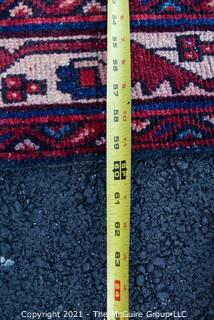 Hand Woven Persian Rug on Red Background. Measures approximately 60" x 89".