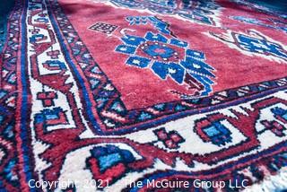 Hand Woven Persian Rug on Red Background. Measures approximately 60" x 89".