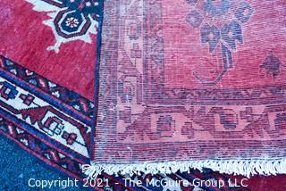 Hand Woven Persian Rug on Red Background. Measures approximately 60" x 89".