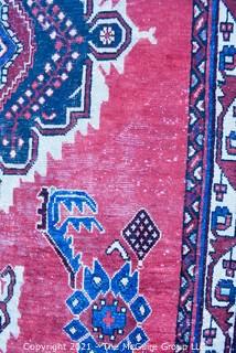 Hand Woven Persian Rug on Red Background. Measures approximately 60" x 89".