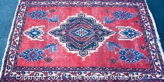 Hand Woven Persian Rug on Red Background. Measures approximately 60" x 89".