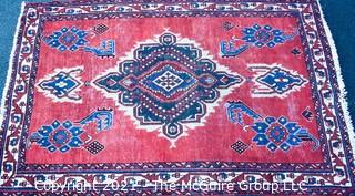 Hand Woven Persian Rug on Red Background. Measures approximately 60" x 89".